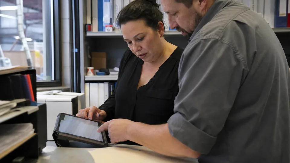 AP specialist and department manager reviewing a supplier invoice approval together at a standing desk