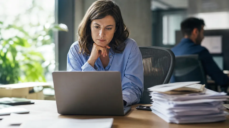 Accounts payable lead comparing a shortlist of AP software vendors on a laptop beside supplier invoices